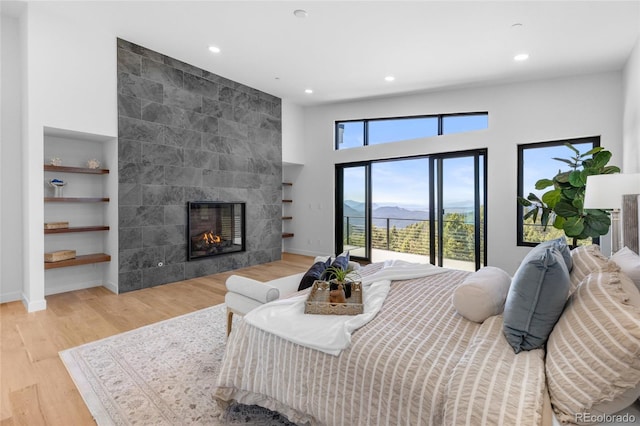 13415 S Resort Dr, Conifer, CO 80433 - bedroom with recessed lighting, access to exterior, light wood-type flooring, a tiled fireplace, and a mountain view