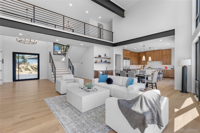 13415 S Resort Dr, Conifer, CO 80433 - living room featuring a high ceiling, light wood finished floors, stairs, beam ceiling, and a chandelier