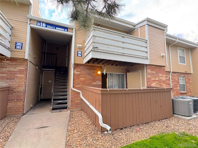 exterior space with cooling unit, brick siding, and a balcony