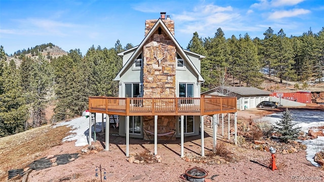 1738 Wildhorn Rd, Florissant, CO 80816 - rear view of property with a chimney, stone siding, a fire pit, and a wooden deck