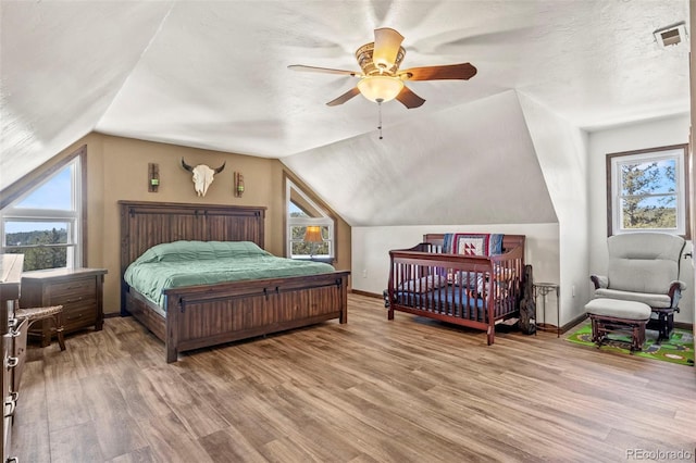 bedroom with vaulted ceiling, wood finished floors, and baseboards