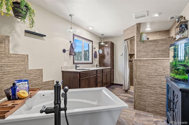 full bath with a soaking tub, double vanity, visible vents, and a sink