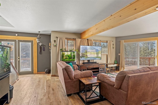 living room with beam ceiling, french doors, light wood-type flooring, and a healthy amount of sunlight