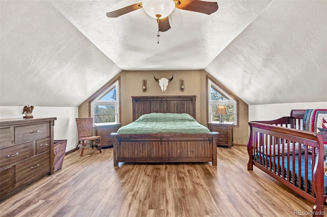 bedroom with baseboards, a textured ceiling, wood finished floors, and vaulted ceiling