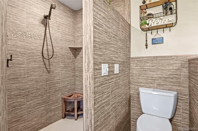 full bath featuring tile walls, toilet, and tiled shower