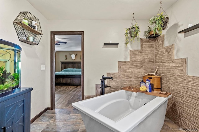 ensuite bathroom featuring a freestanding bath, ensuite bath, tile walls, and a sink