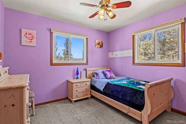 carpeted bedroom featuring baseboards, multiple windows, and a ceiling fan