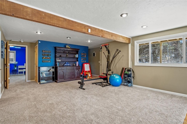 exercise room with carpet, baseboards, and a textured ceiling