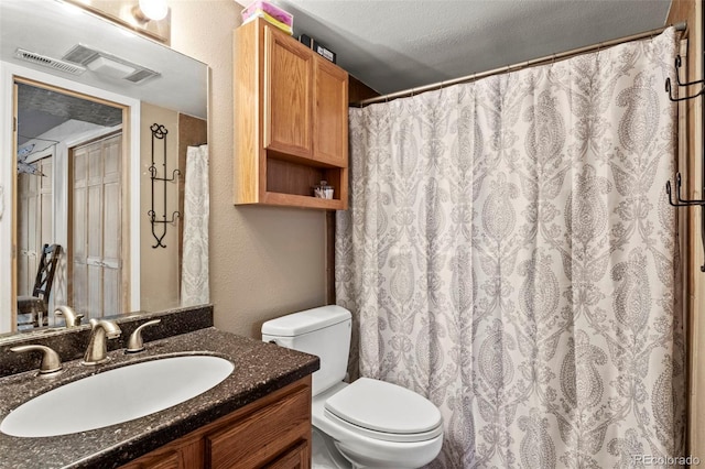 full bath with visible vents, toilet, vanity, a textured wall, and a textured ceiling