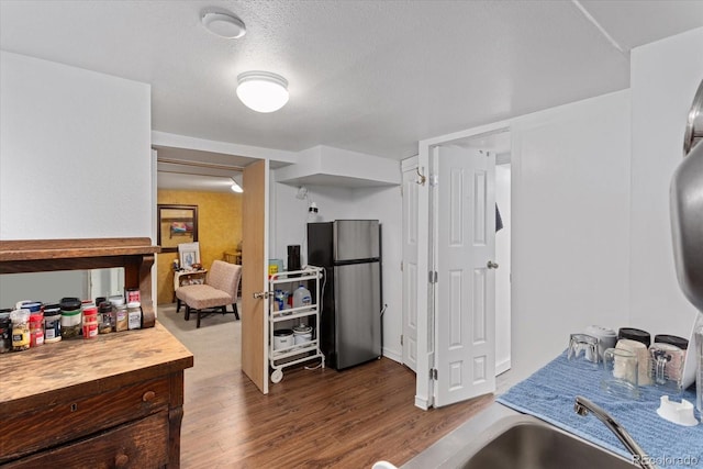 kitchen with sink, hardwood / wood-style flooring, stainless steel refrigerator, and a textured ceiling