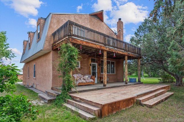 back of property featuring a wooden deck and a lawn