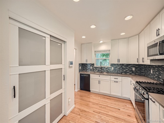 kitchen with appliances with stainless steel finishes, sink, and white cabinetry