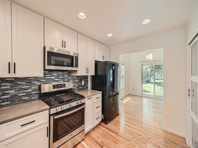 kitchen featuring appliances with stainless steel finishes, backsplash, light hardwood / wood-style flooring, and white cabinets