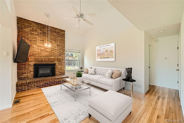 living room with high vaulted ceiling, wood-type flooring, ceiling fan, and a fireplace