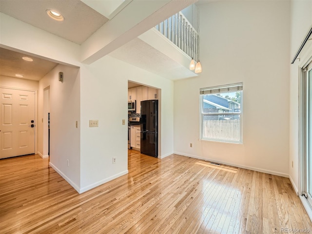 interior space with beam ceiling and light hardwood / wood-style floors