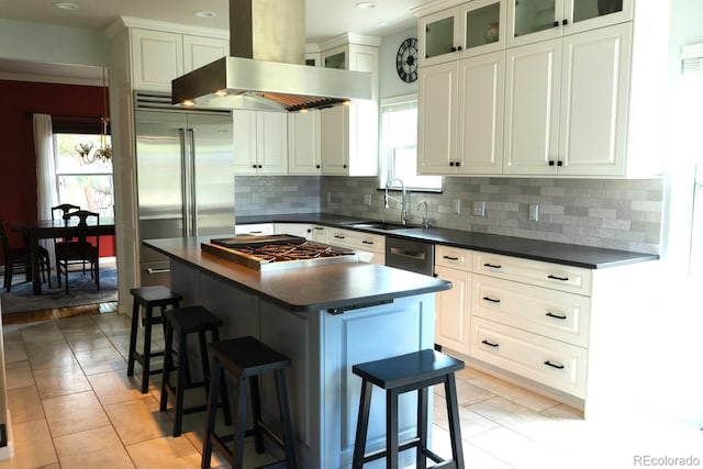 kitchen with wall chimney range hood, a sink, dark countertops, appliances with stainless steel finishes, and recessed lighting
