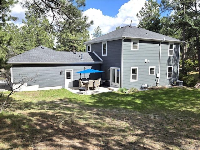 rear view of property with a patio, a yard, and a shingled roof