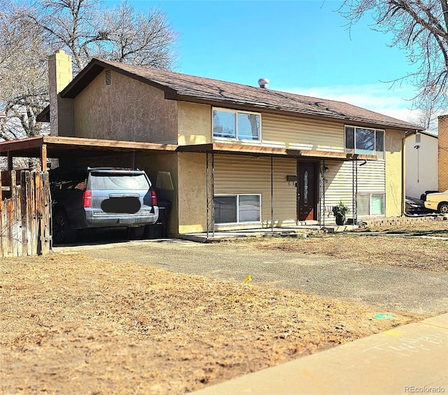 split foyer home with driveway, a chimney, and stucco siding