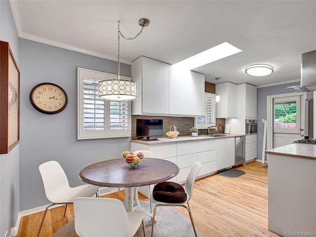 3481 S Race St, Englewood, CO 80113 - kitchen with appliances with stainless steel finishes, ornamental molding, white cabinetry, light wood finished floors, and tasteful backsplash