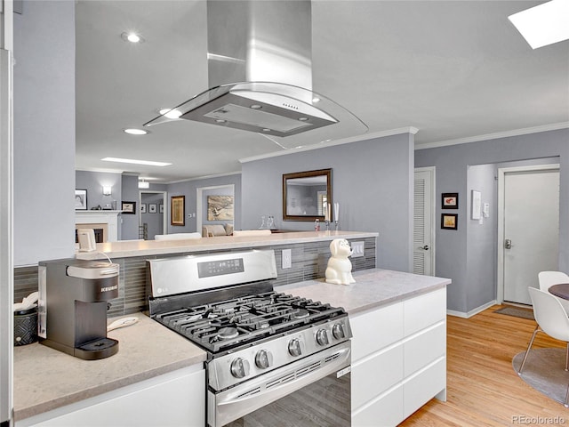 3481 S Race St, Englewood, CO 80113 - kitchen featuring stainless steel gas range oven, island range hood, crown molding, white cabinetry, and light wood-type flooring