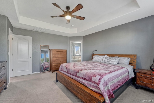 bedroom with light carpet, ceiling fan, and a raised ceiling