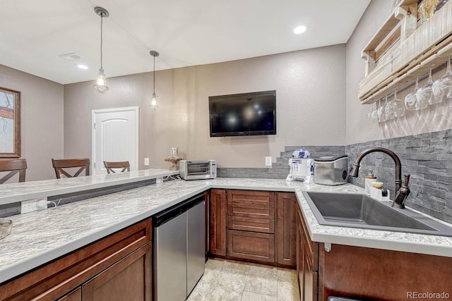 kitchen with stainless steel fridge, backsplash, a breakfast bar area, decorative light fixtures, and sink