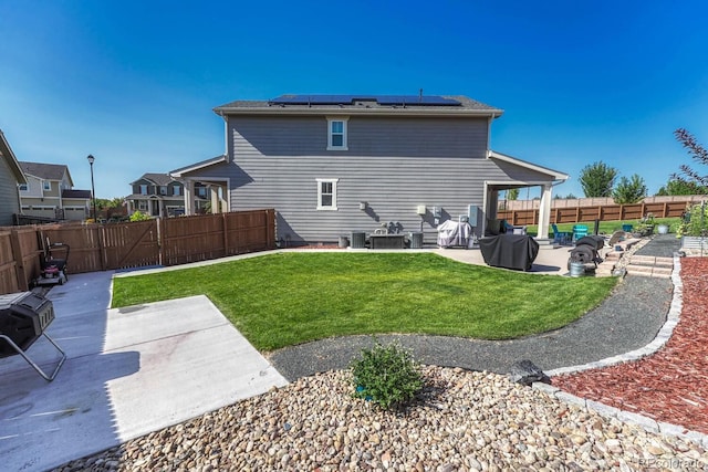 rear view of house featuring solar panels, a lawn, and a patio