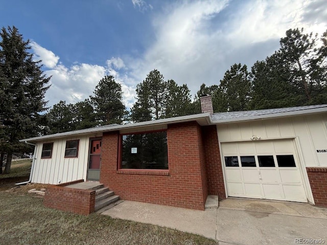 1013 Lexington Ln, Estes Park, CO 80517 - ranch-style house with board and batten siding, a chimney, an attached garage, brick siding, and concrete driveway