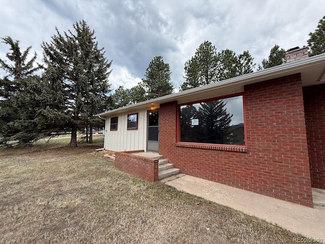 1013 Lexington Ln, Estes Park, CO 80517 - ranch-style home with board and batten siding, a chimney, brick siding, and a front lawn
