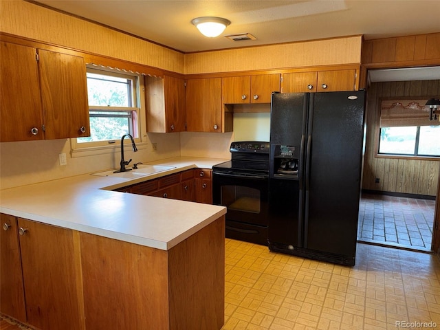 1013 Lexington Ln, Estes Park, CO 80517 - kitchen featuring black appliances, brown cabinetry, light countertops, healthy amount of natural light, and wood walls