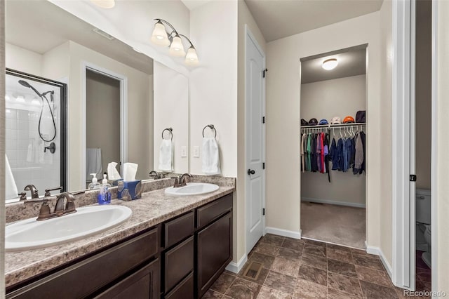 1868 Homestead Dr, Fort Lupton, CO 80621 - full bathroom featuring a stall shower, baseboards, double vanity, a spacious closet, and stone finish floors