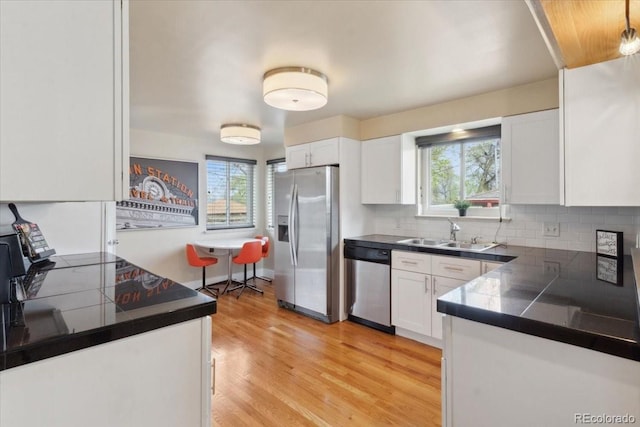 kitchen with a sink, a wealth of natural light, appliances with stainless steel finishes, and white cabinetry