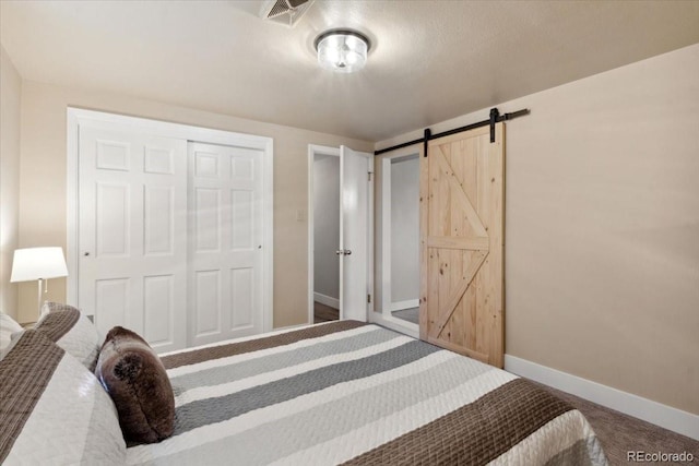 bedroom featuring a closet, baseboards, carpet floors, a barn door, and visible vents