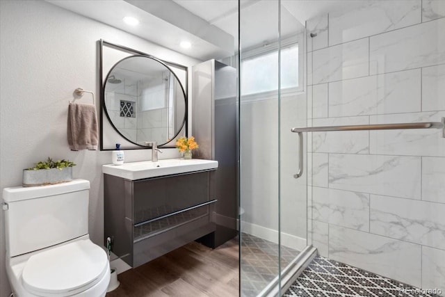 bathroom with toilet, a shower stall, vanity, and wood finished floors