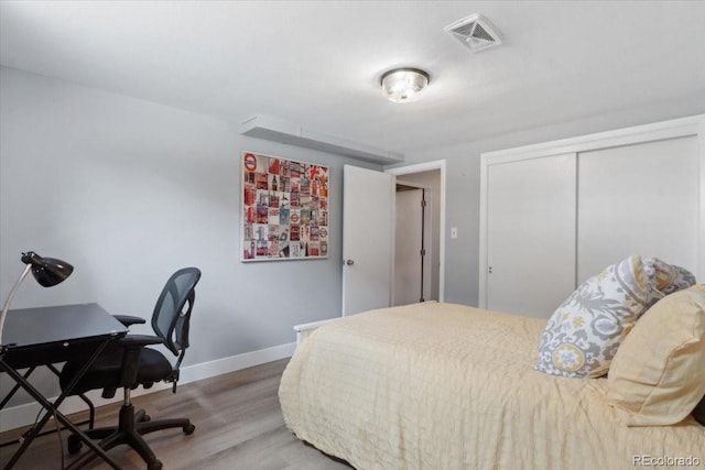 bedroom with visible vents, baseboards, a closet, and wood finished floors
