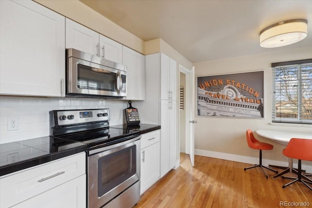 kitchen with white cabinets, stainless steel appliances, light wood-type flooring, baseboards, and decorative backsplash