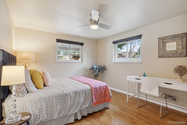 bedroom featuring wood finished floors, a ceiling fan, baseboards, and multiple windows
