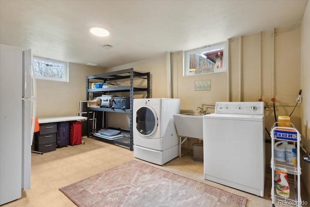 clothes washing area featuring washing machine and clothes dryer, a sink, and light floors