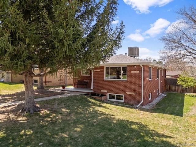 view of front of home with brick siding, a front lawn, fence, and a patio