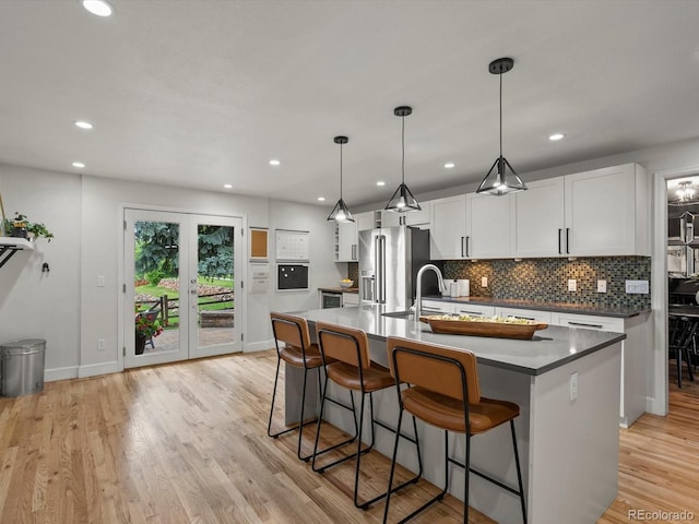 7055 E Heritage Pl S, Centennial, CO 80111 - kitchen featuring high quality fridge, tasteful backsplash, a breakfast bar area, a kitchen island with sink, and baseboards