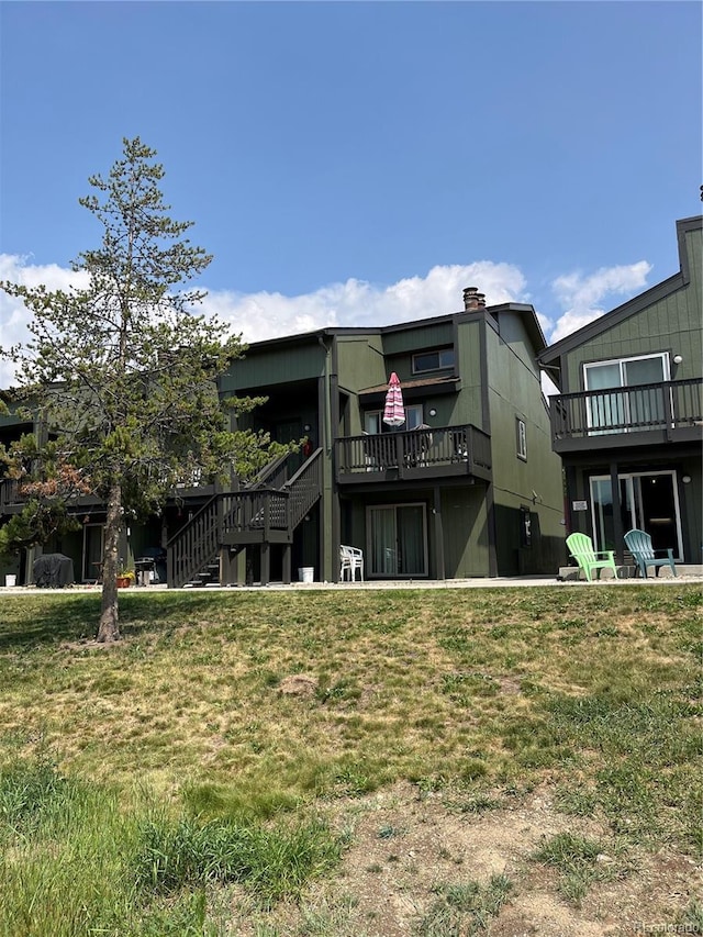 rear view of house with stairs and a yard