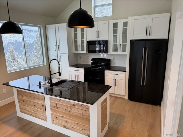 kitchen featuring tasteful backsplash, light wood-style floors, white cabinetry, a sink, and black appliances