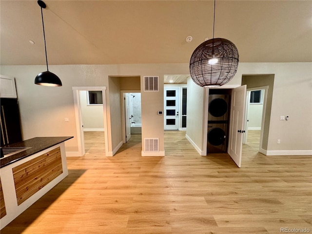 interior space featuring stacked washer / dryer, light wood-type flooring, and visible vents