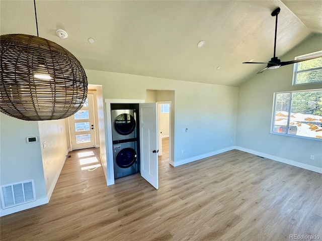 interior space featuring light wood-type flooring, stacked washer and clothes dryer, visible vents, and baseboards