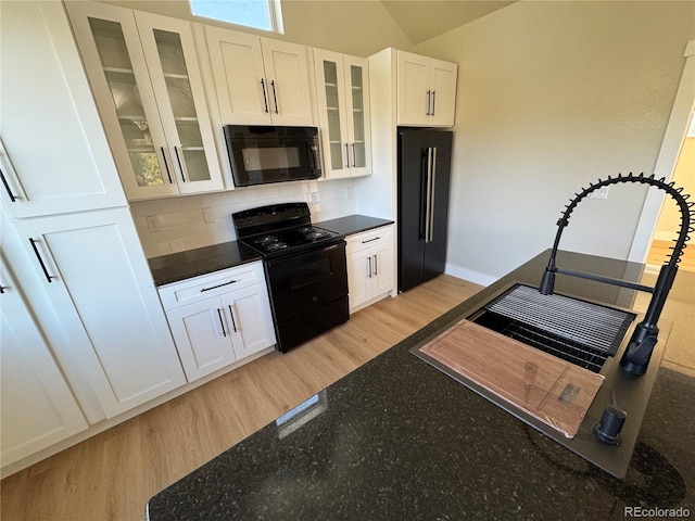 kitchen with white cabinets, decorative backsplash, black appliances, light wood finished floors, and glass insert cabinets