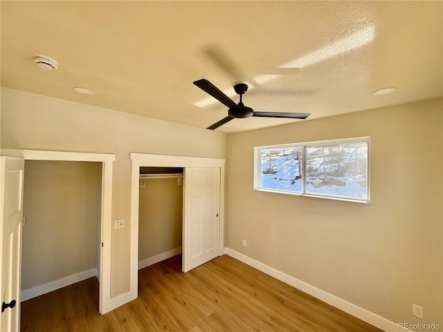 unfurnished bedroom with ceiling fan, a closet, baseboards, and wood finished floors