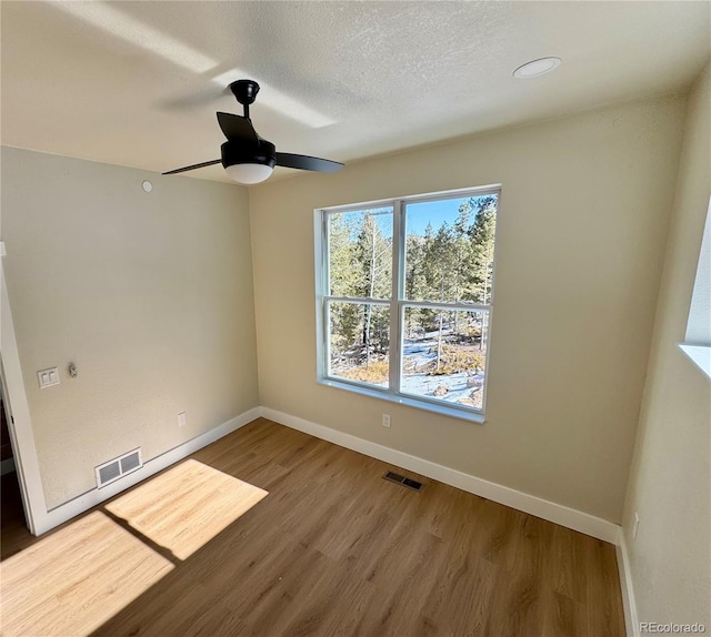 unfurnished room featuring baseboards, a textured ceiling, visible vents, and wood finished floors