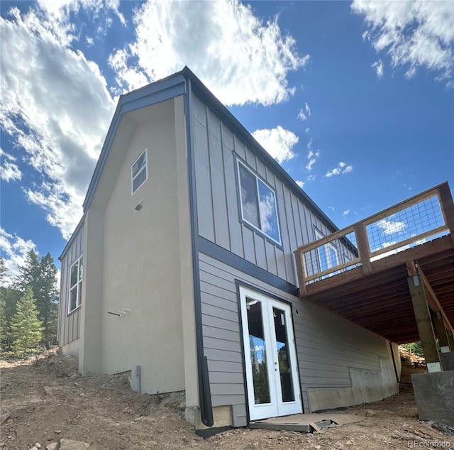 rear view of property with french doors, board and batten siding, and a wooden deck