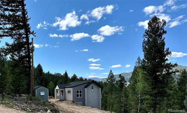 exterior space featuring a storage shed, an outdoor structure, a mountain view, and a view of trees