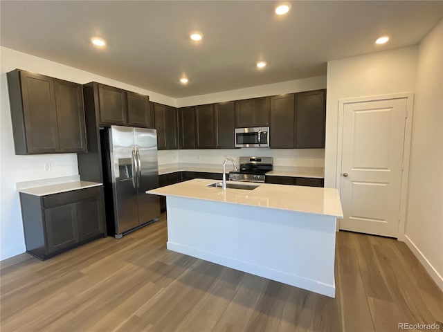 kitchen featuring dark brown cabinetry, sink, appliances with stainless steel finishes, and light hardwood / wood-style flooring